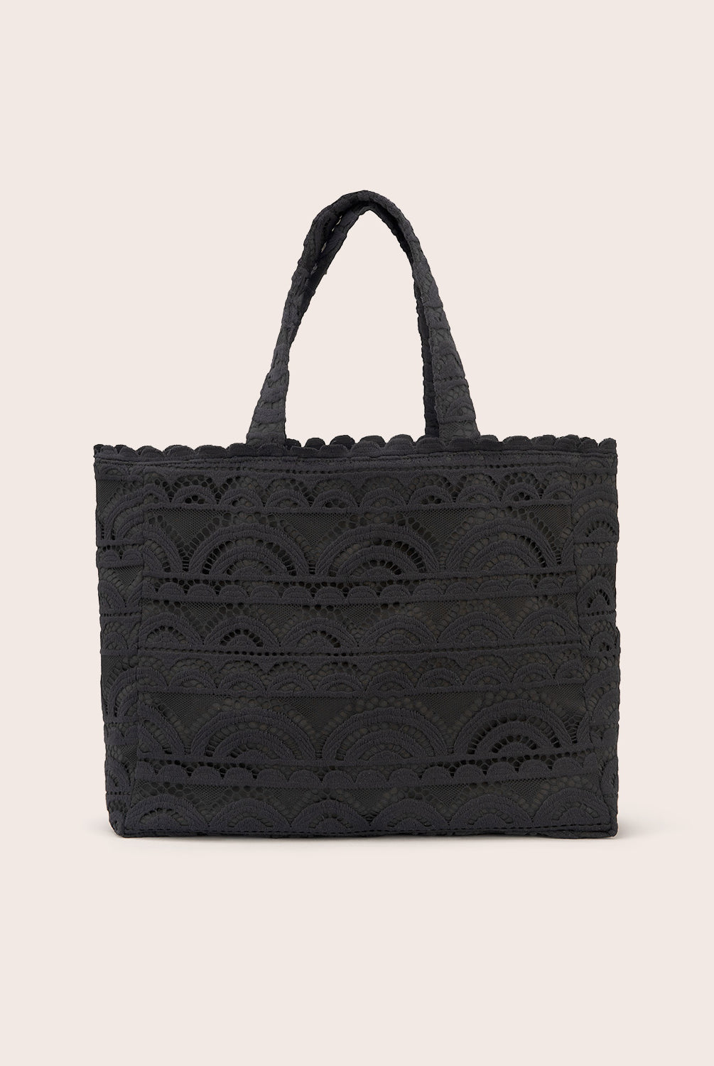 A black lace tote with scalloped trim against a white wall