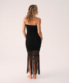 Woman wearing a black strapless dress with fringe details on a white background