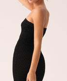 Black strapless dress worn by a model on a white background