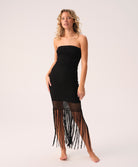 Woman wearing a black strapless dress with fringe details on a white background