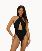 Woman wearing a black one piece in front of a white background.