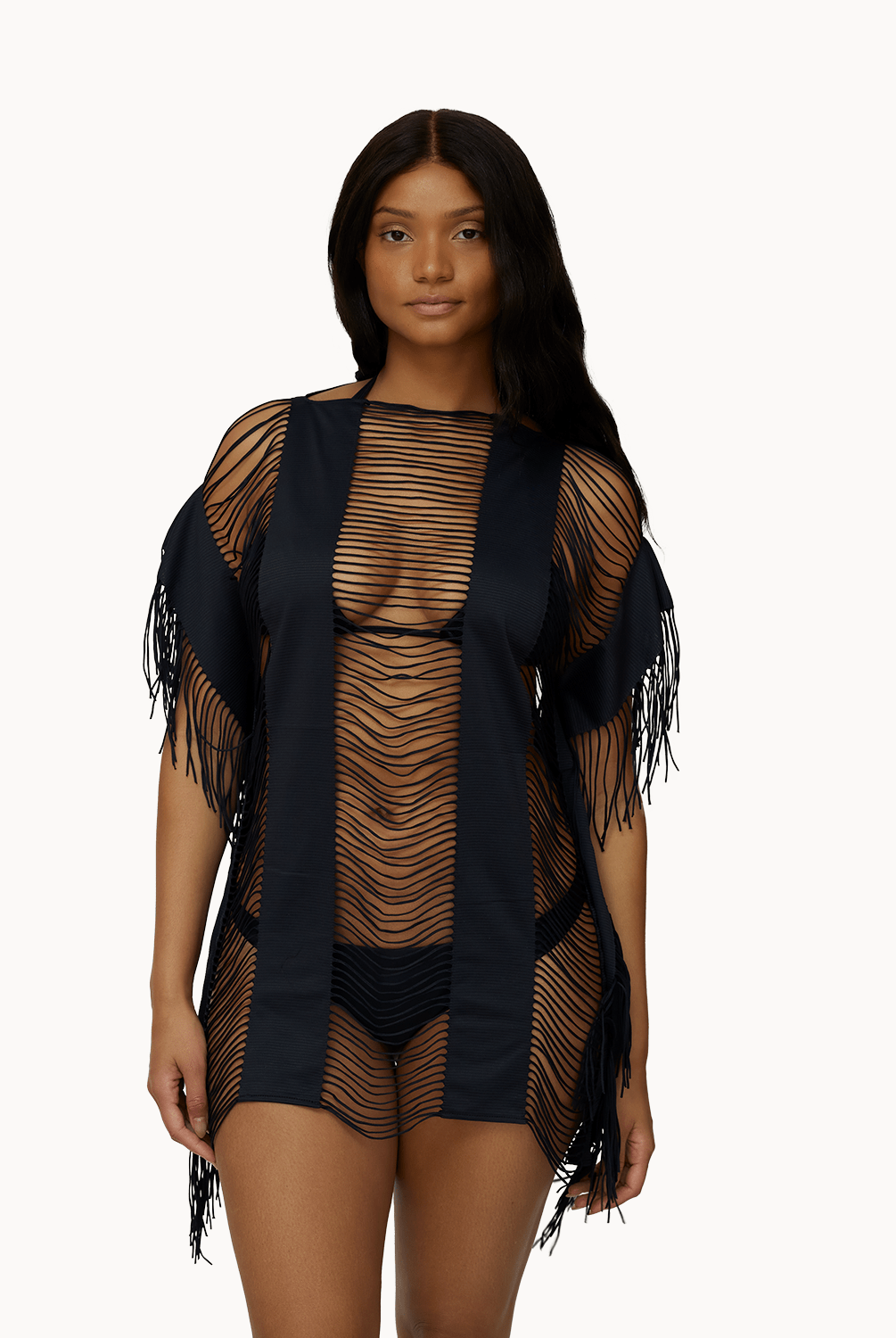 Woman wearing black fringe cover up in front of a white background.