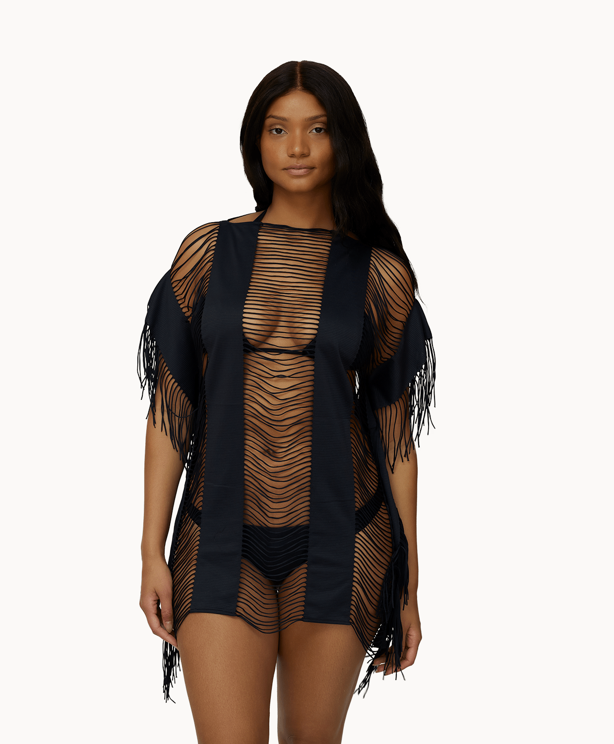 Woman wearing black fringe cover up in front of a white background.
