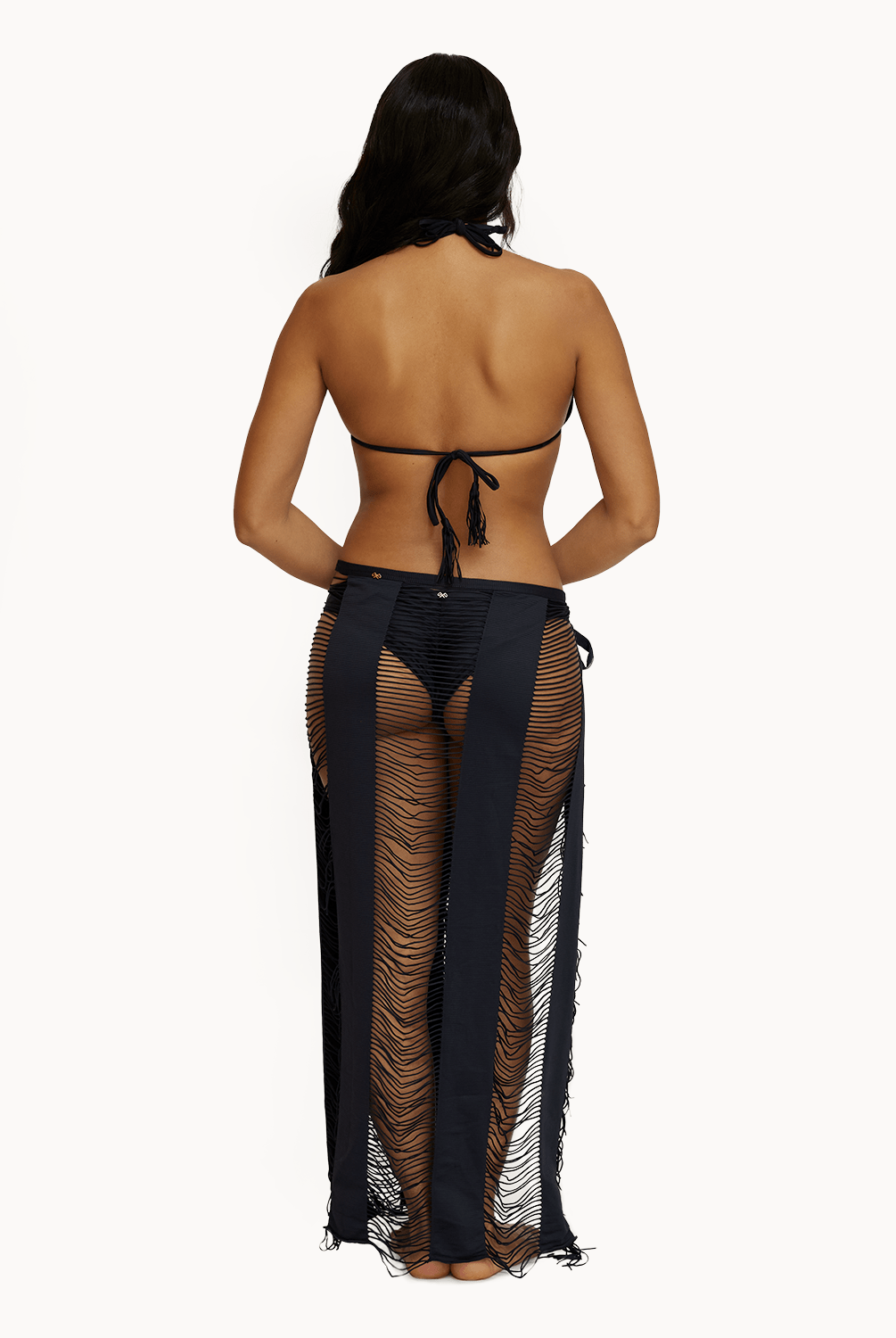 Back view of woman wearing black sarong in front of a white background.