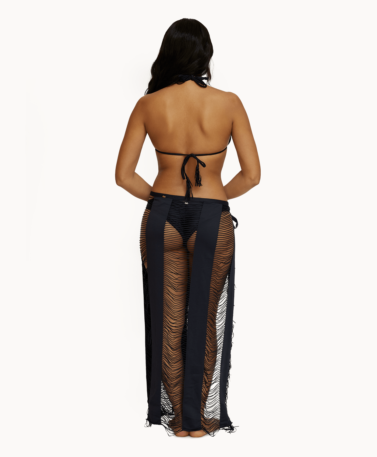 Back view of woman wearing black sarong in front of a white background.
