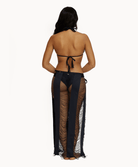 Back view of woman wearing black sarong in front of a white background.
