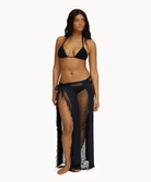 Woman wearing black sarong in front of a white background.