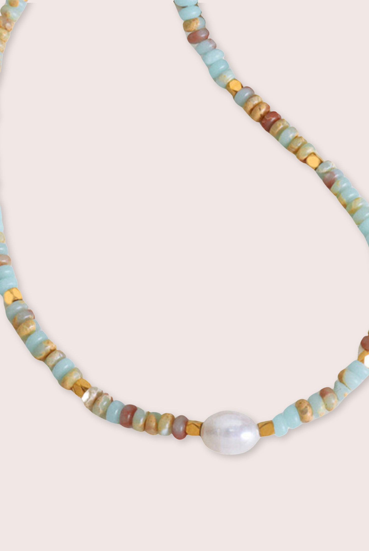 A multi colored necklace with a white pearl against a white wall.