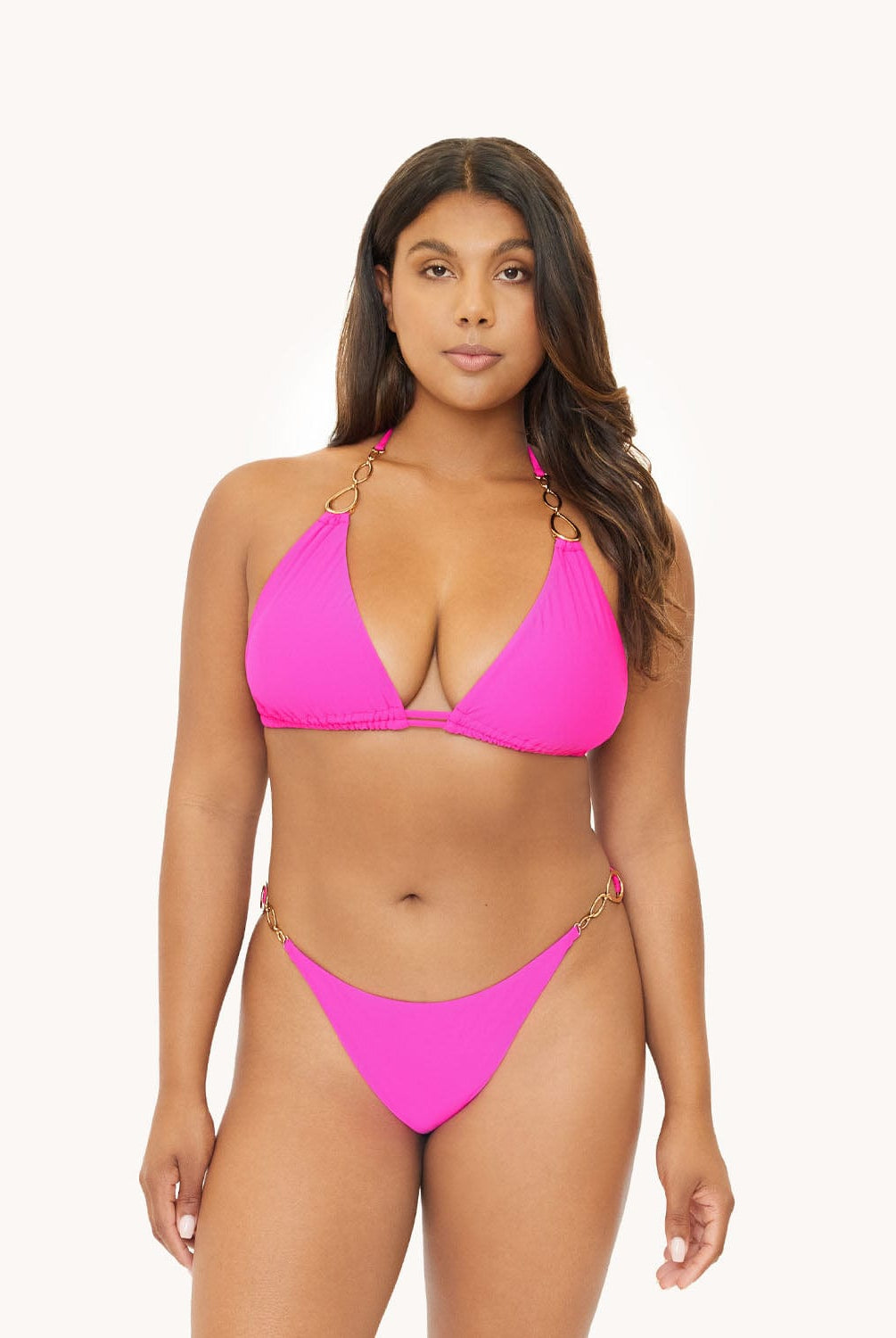 Brunette woman wearing a neon pink bikini in front of a white background.