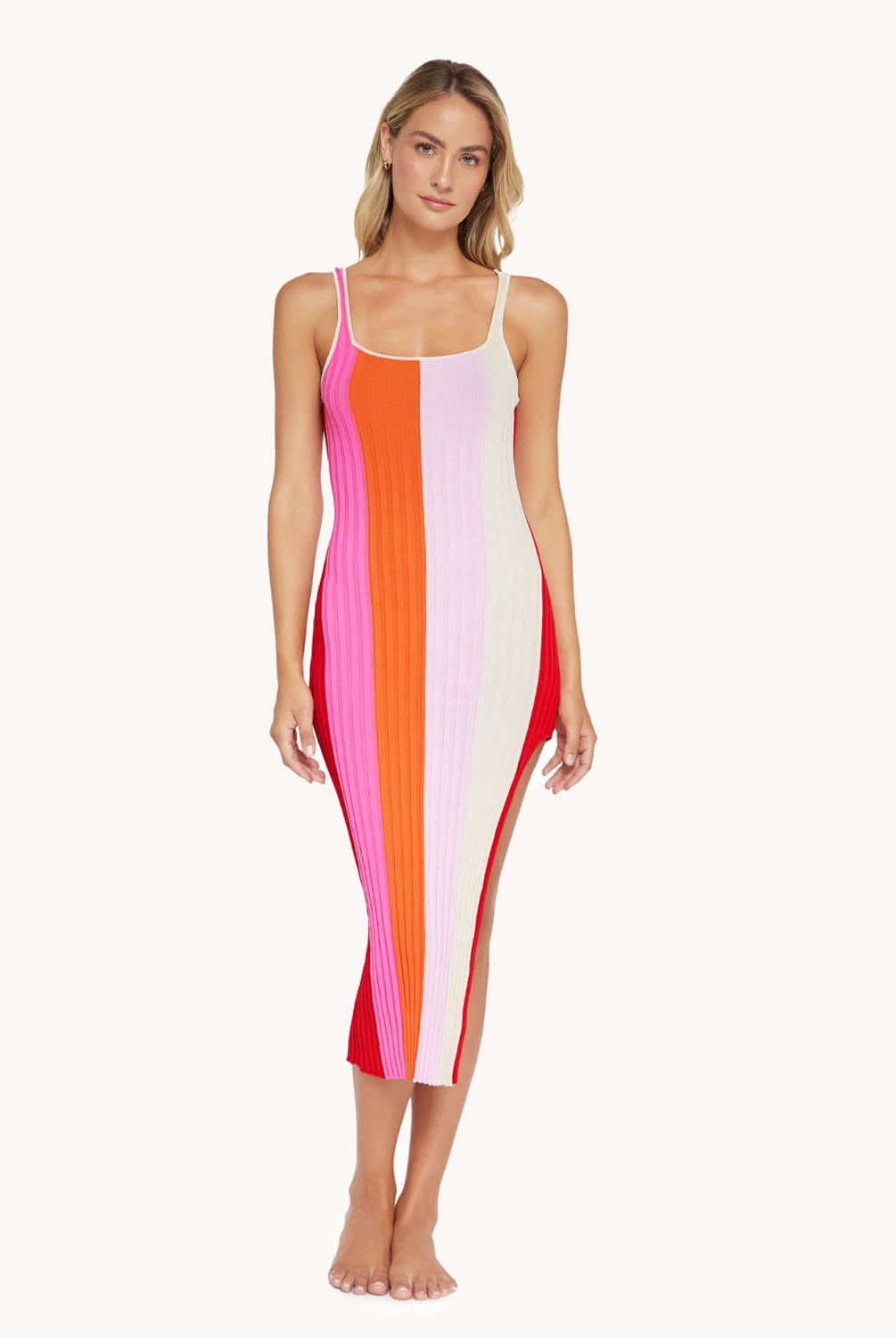 Blonde woman wearing a slit dress in front of a white background.