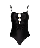 A black one piece swimsuit against a white wall.