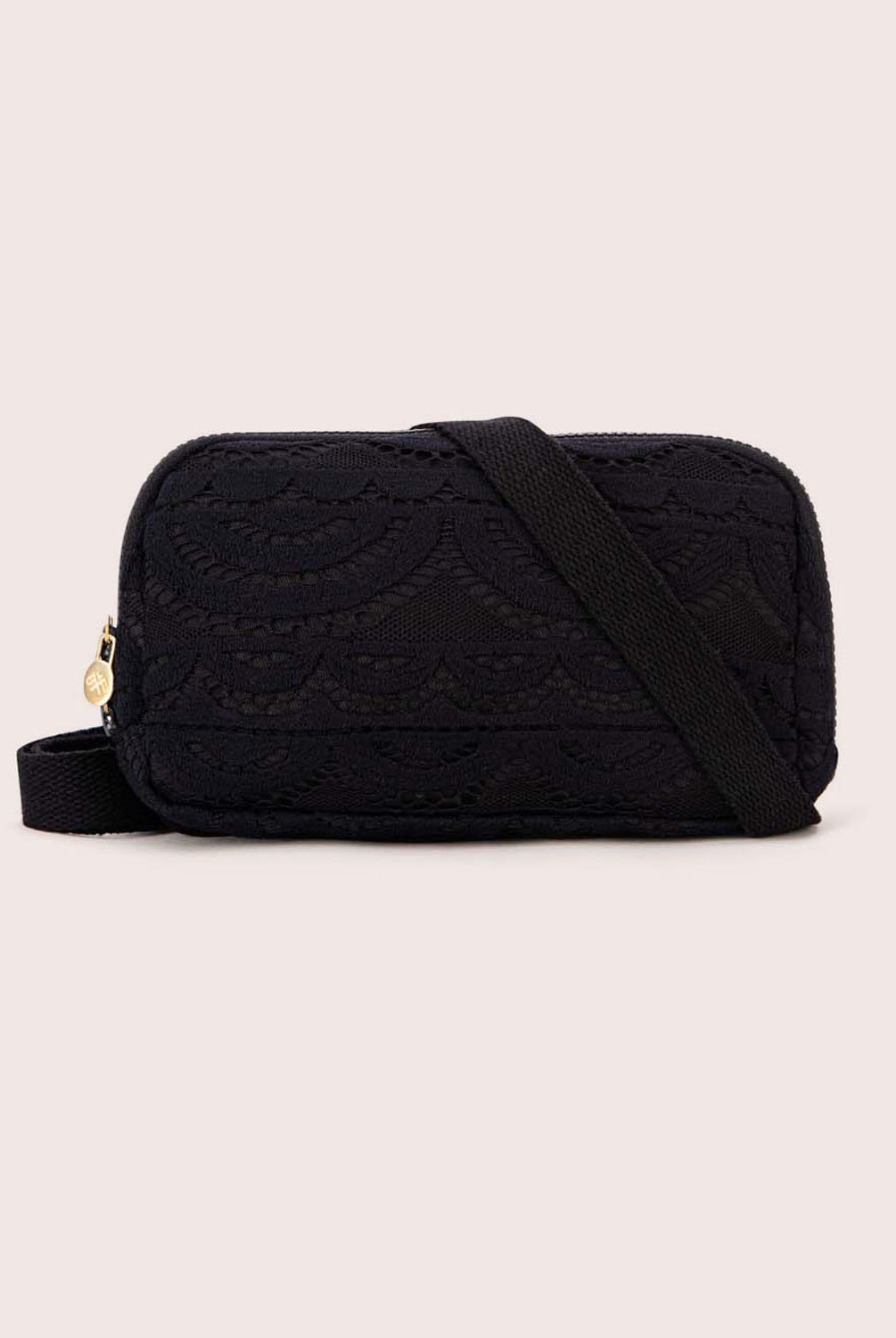 A black lace crossbody bag against a white wall.