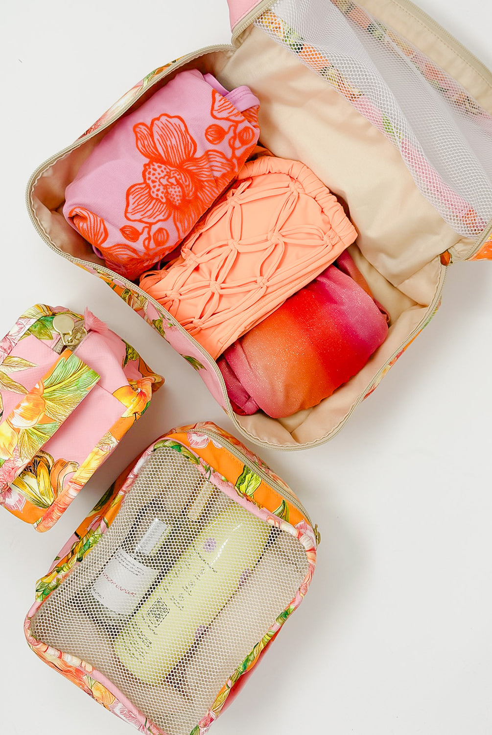 Three packing cubes with travel essentials packed inside.