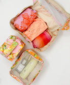 Three packing cubes with travel essentials packed inside.