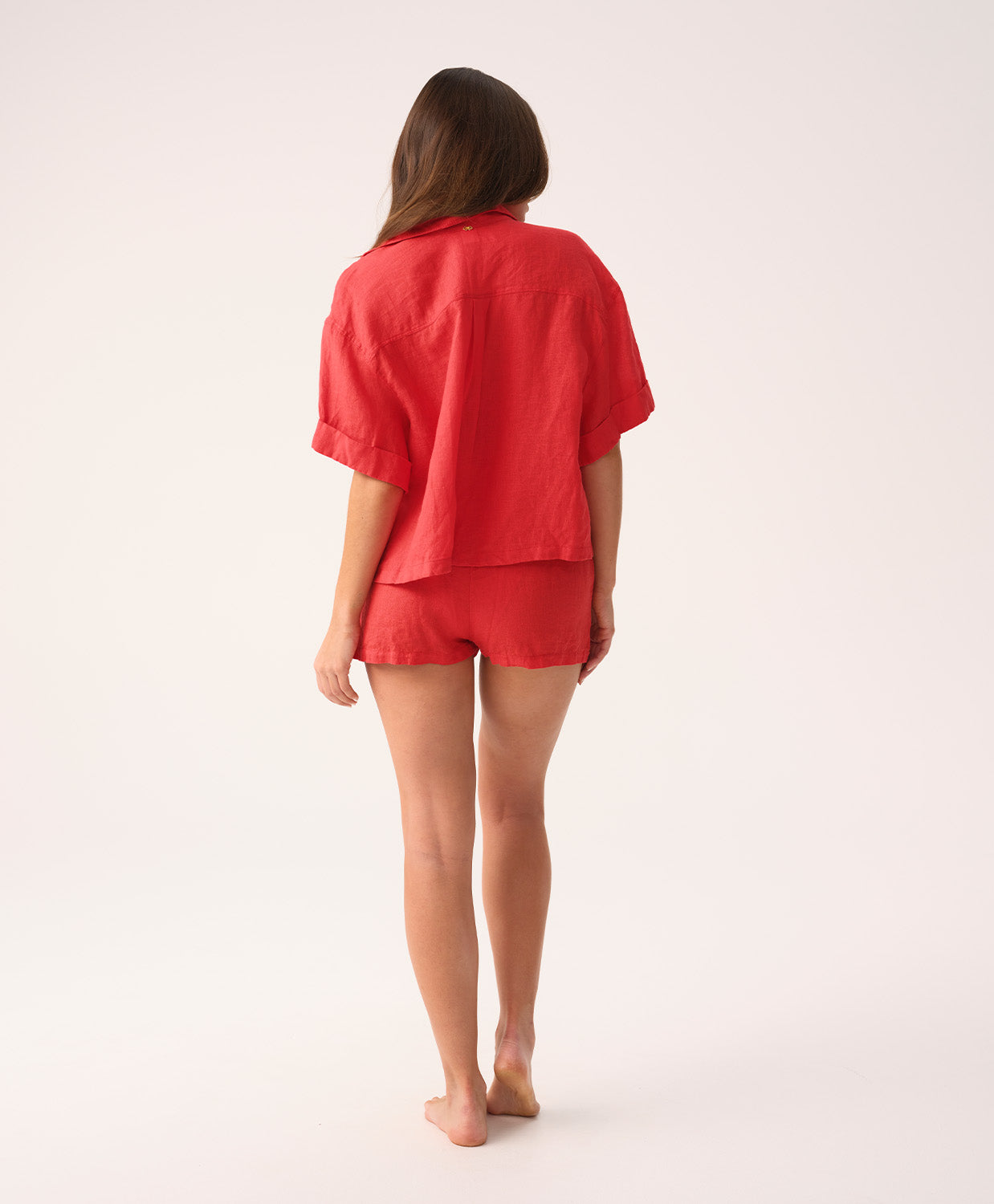 Woman wearing a red shirt and short set on a white background