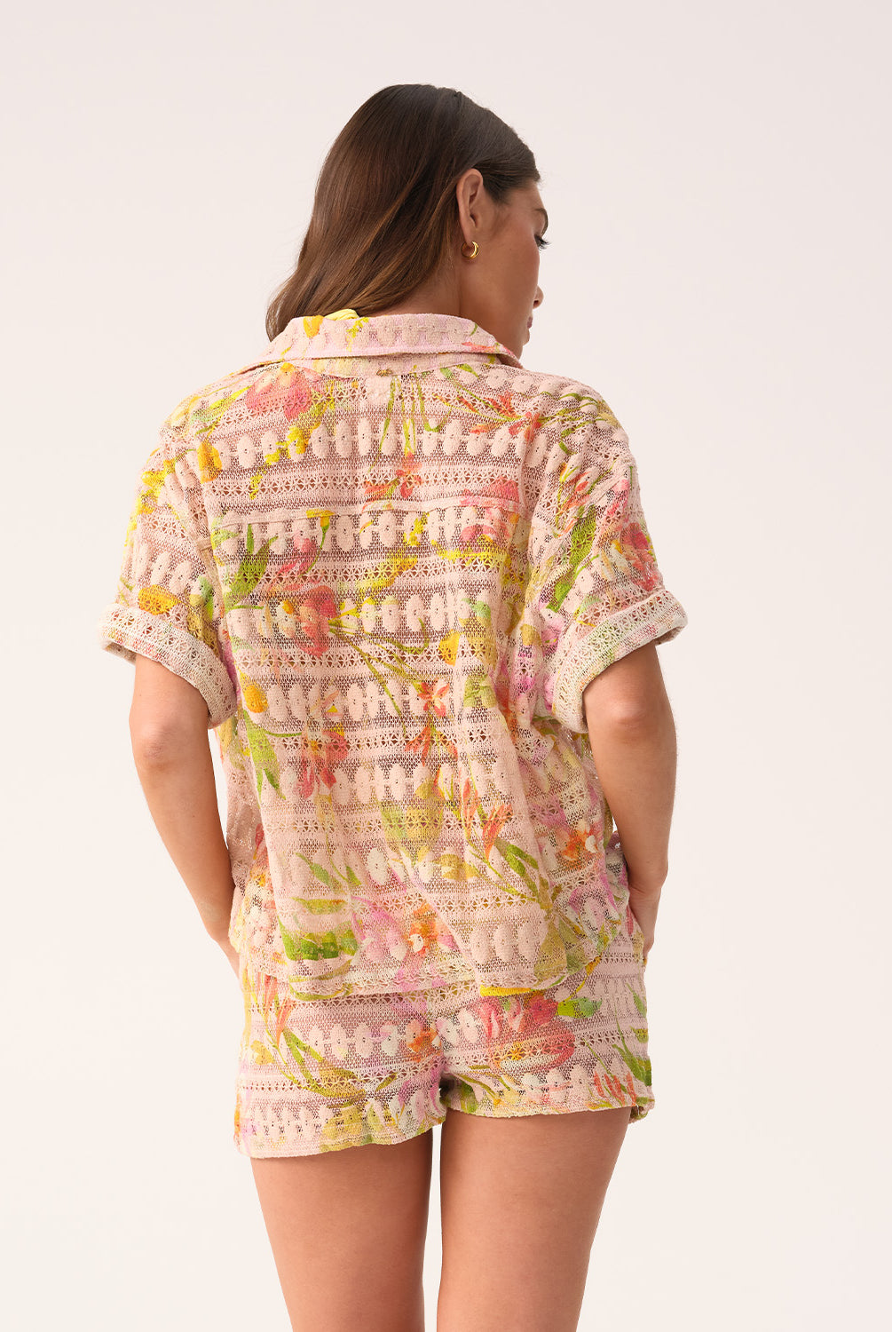 Woman wearing a colorful patterned shirt and shorts on a white background