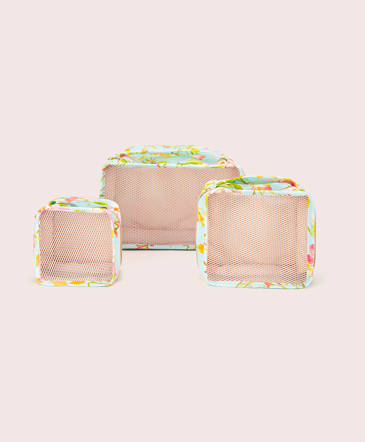 Three mesh packing cubes with floral patterns on a light beige background