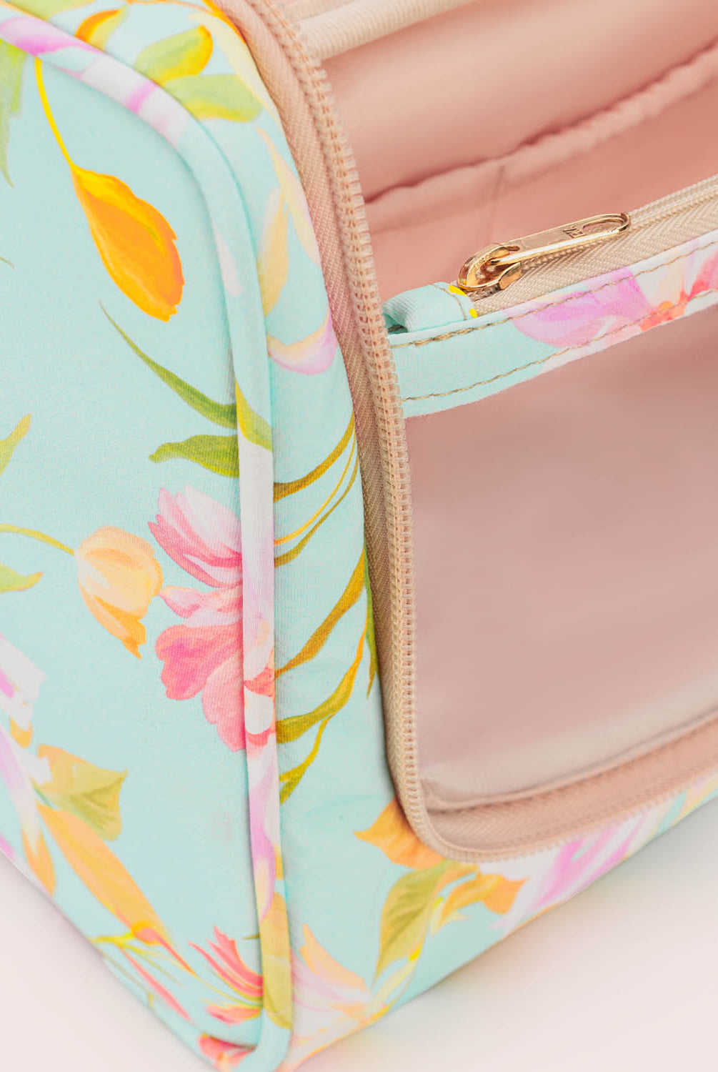 Floral-patterned cosmetic bag with a pink interior on a light background
