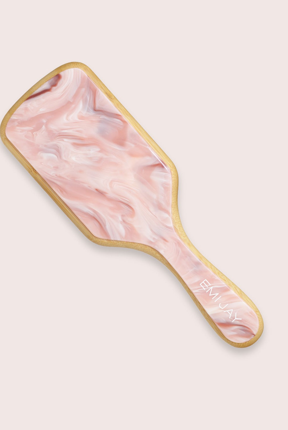 A pink hair brush against a white wall.