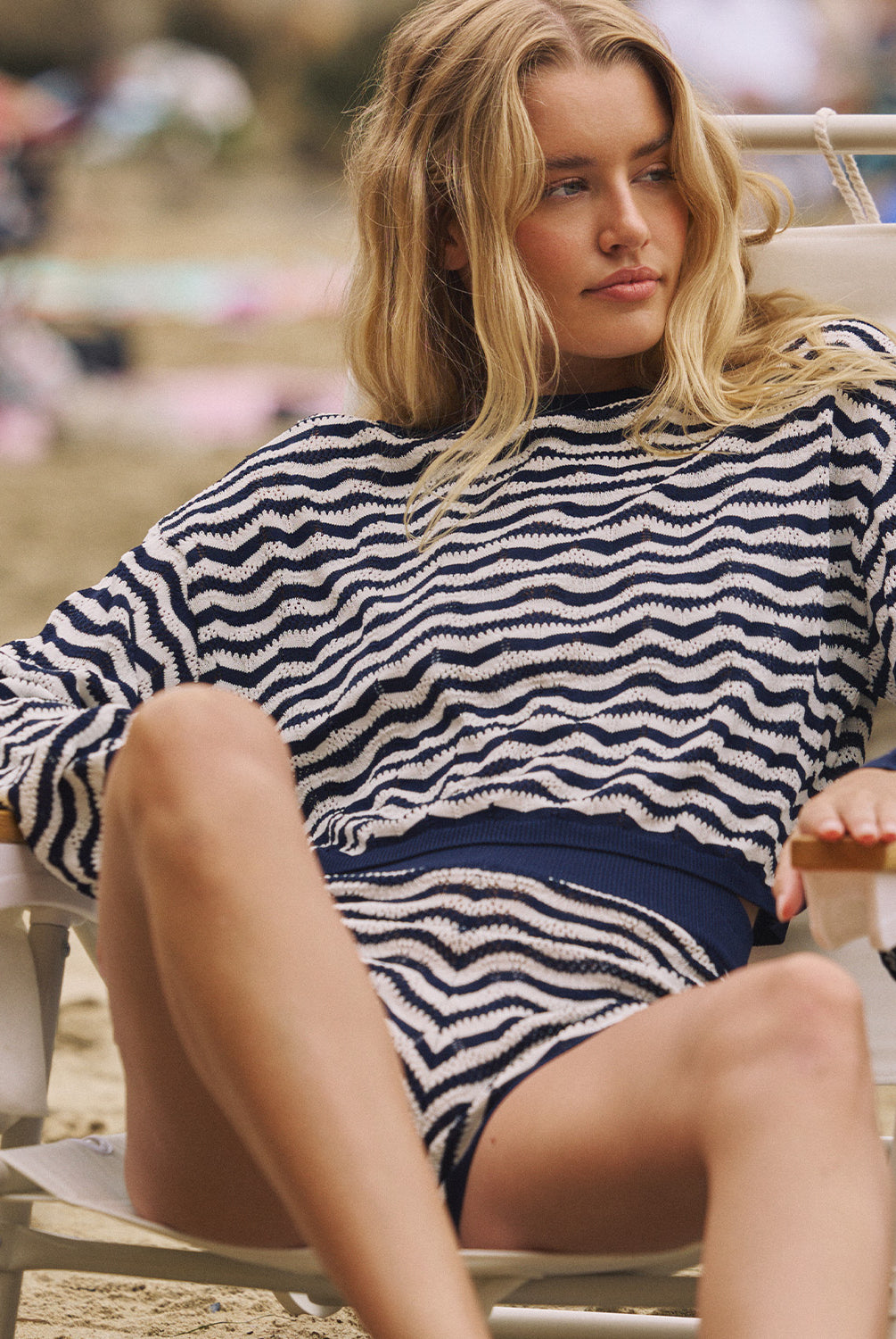 A woman wearing a long sleeve blue and white striped knit shirt and matching shorts sitting on a beach chair.