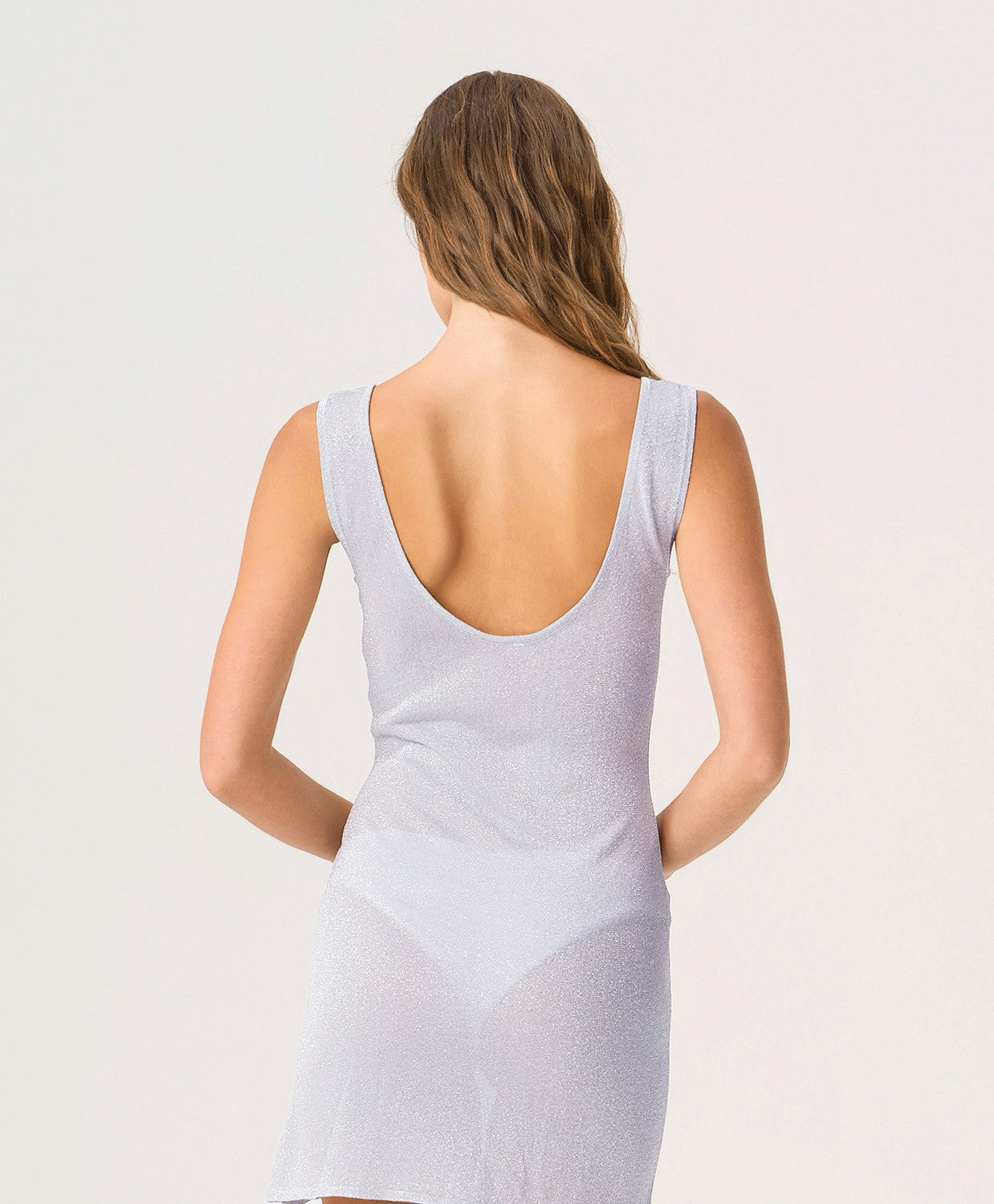 Woman wearing a light gray tank dress against a plain background