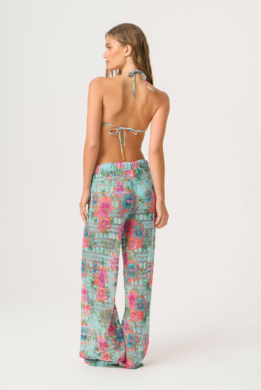 Woman wearing a floral print triangle top and pants on a white background