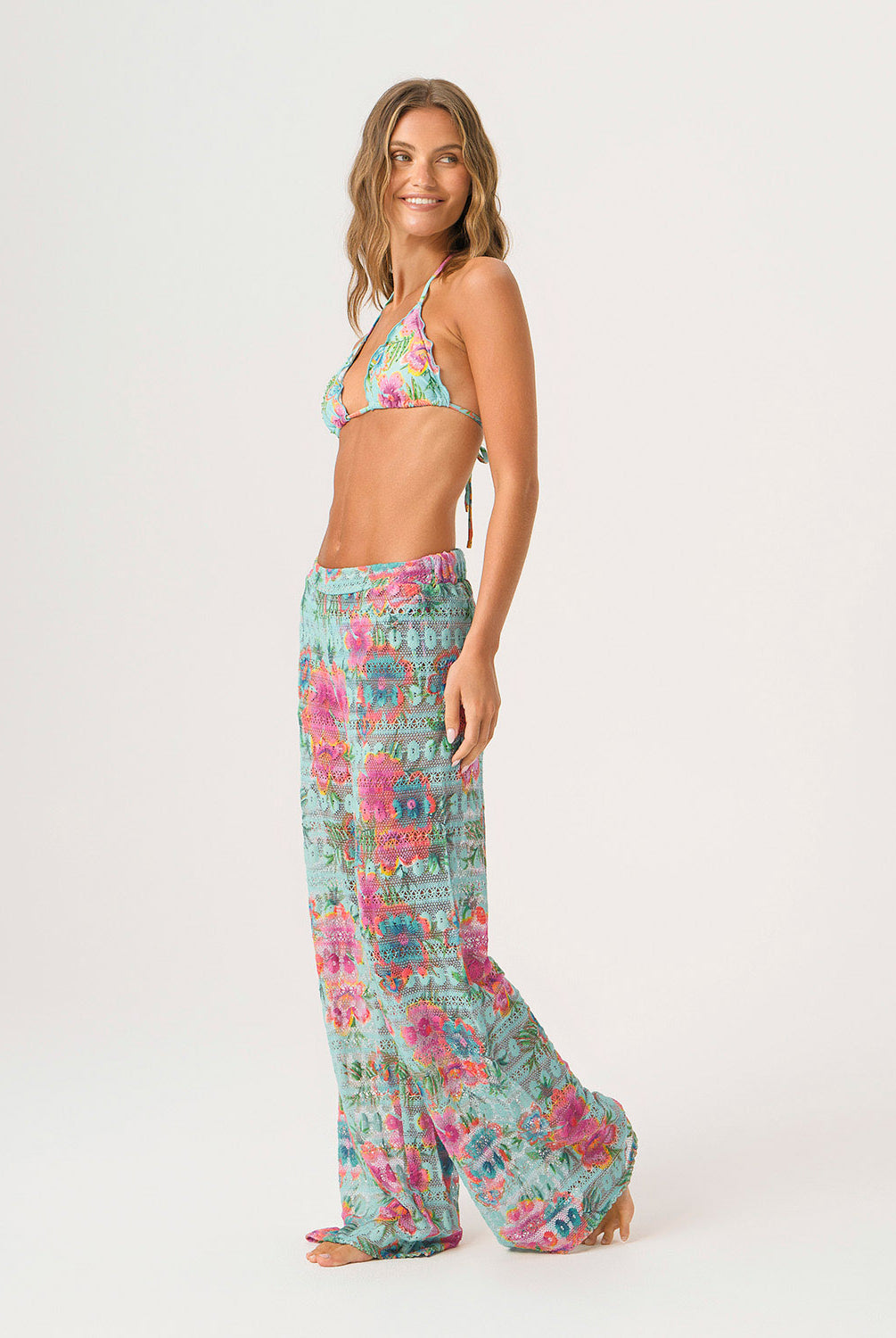 Woman wearing a floral bikini set and matching pants on a white background