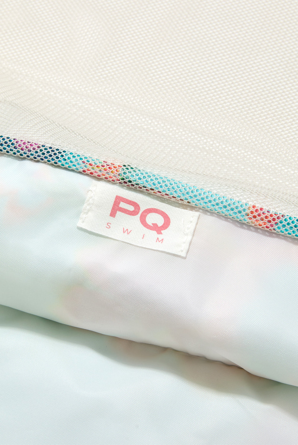 Close-up of a PQ Swim branded product with a textured strap on a white background