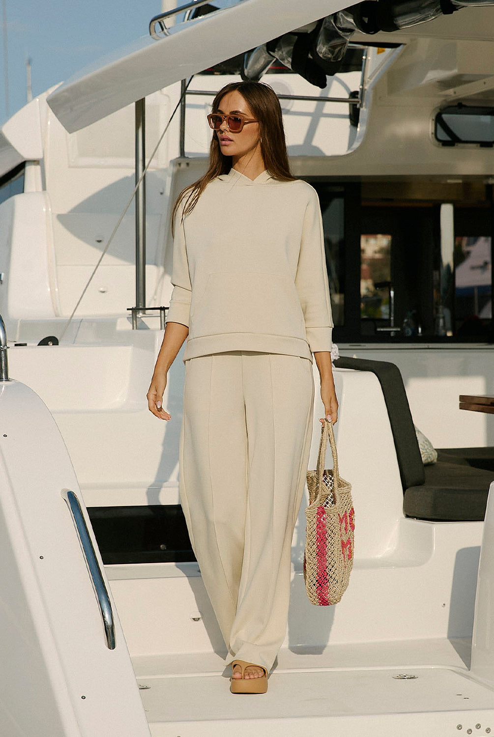 Woman in a beige outfit standing on a yacht
