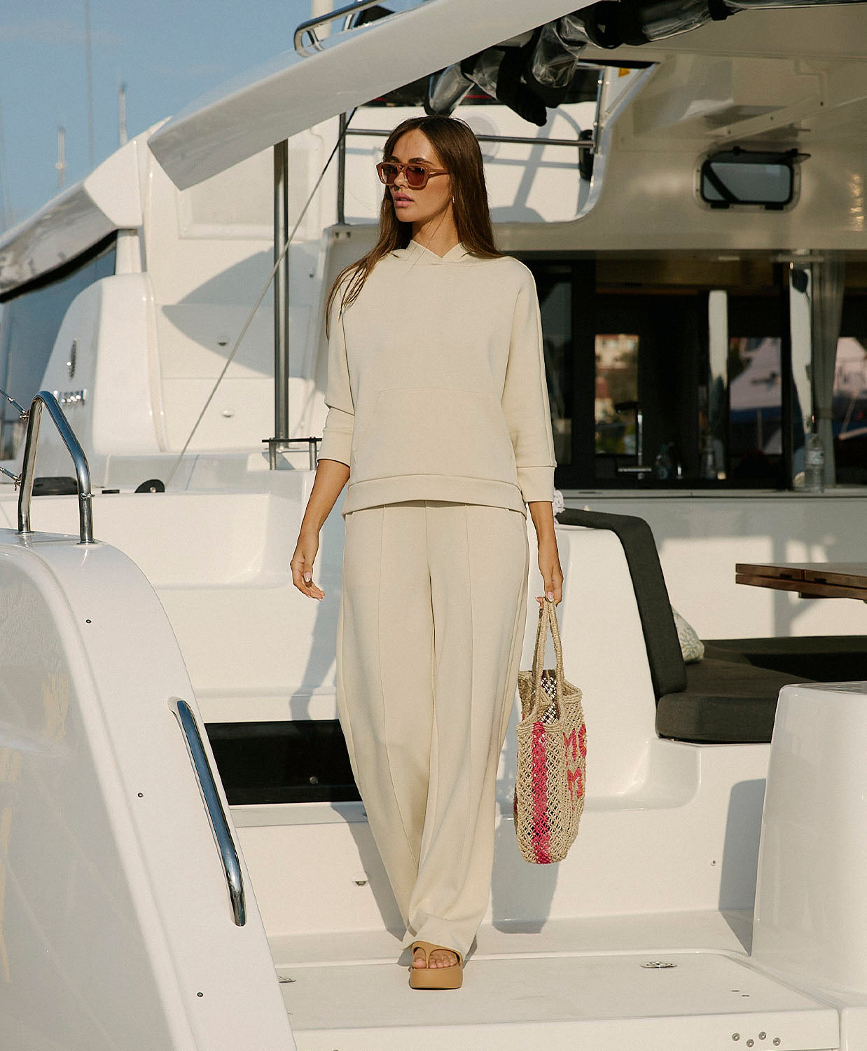 Woman in a beige outfit standing on a yacht