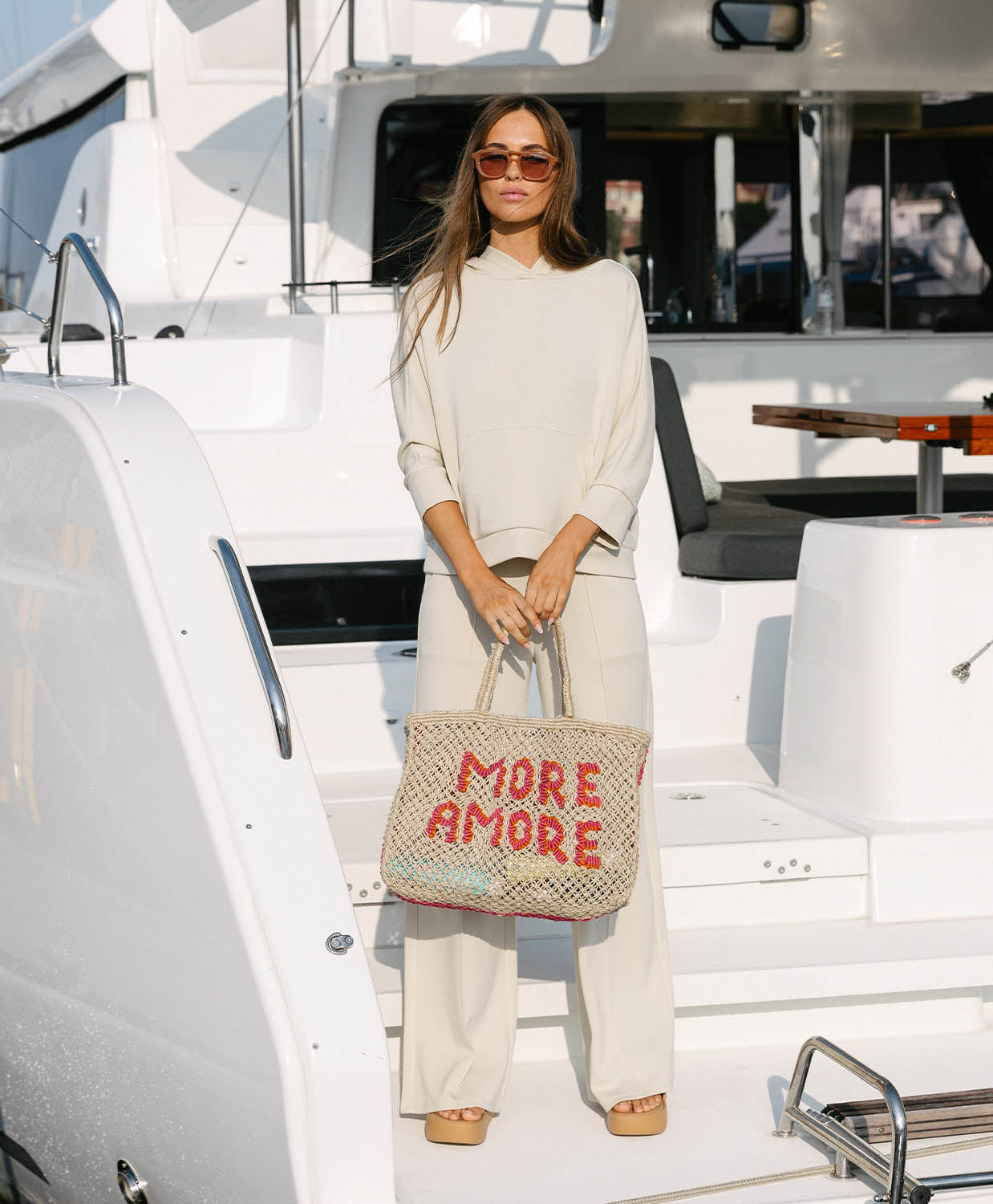 Woman holding a 'More Amore' bag on a boat
