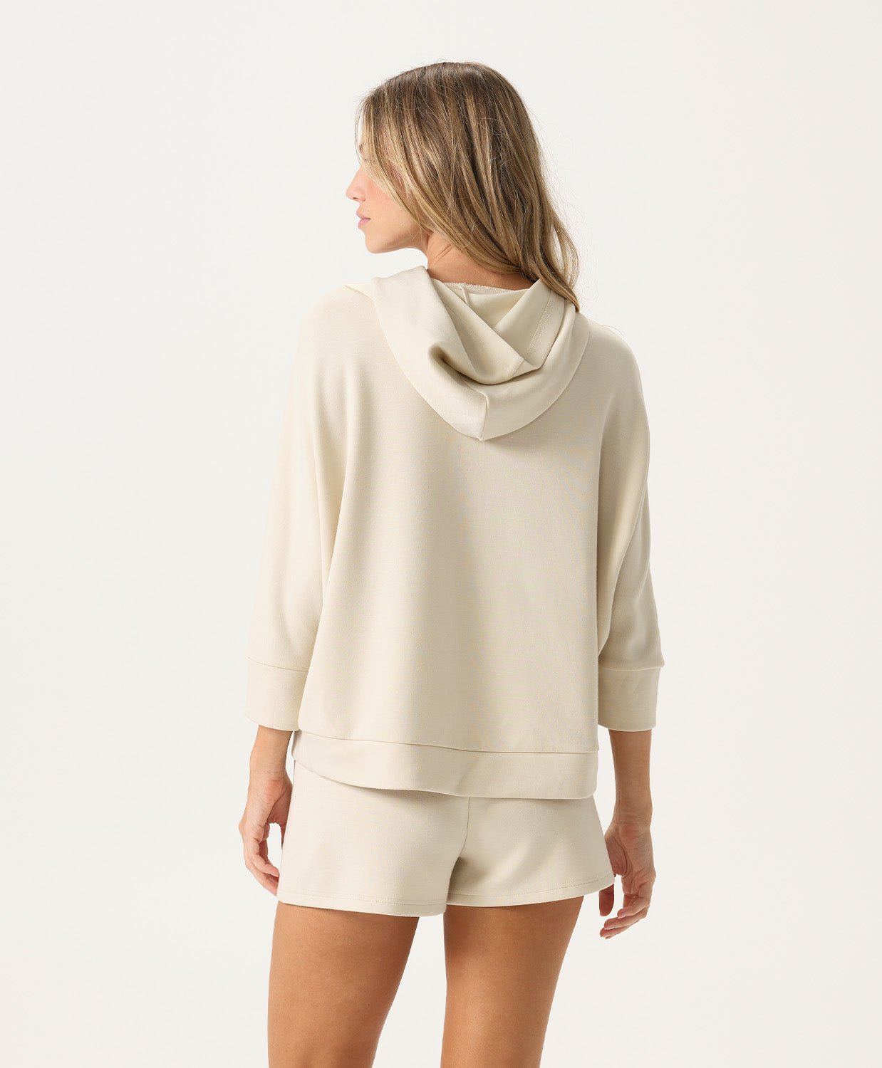Woman wearing a beige hoodie and shorts set on a white background