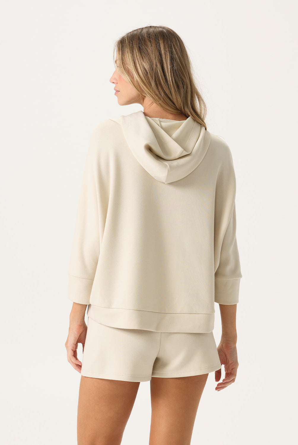 Woman wearing a beige hoodie and shorts set on a white background
