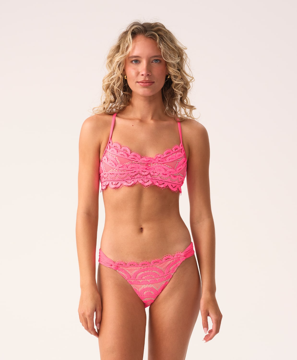 Woman wearing a pink lace bikini against a white background