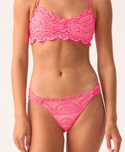 Person wearing a pink lace bikini set on a plain background