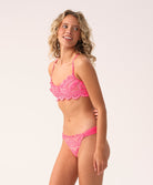 Woman wearing a pink lace bikini against a white background