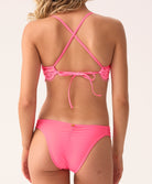 Woman wearing a pink bikini with criss-cross straps on a white background