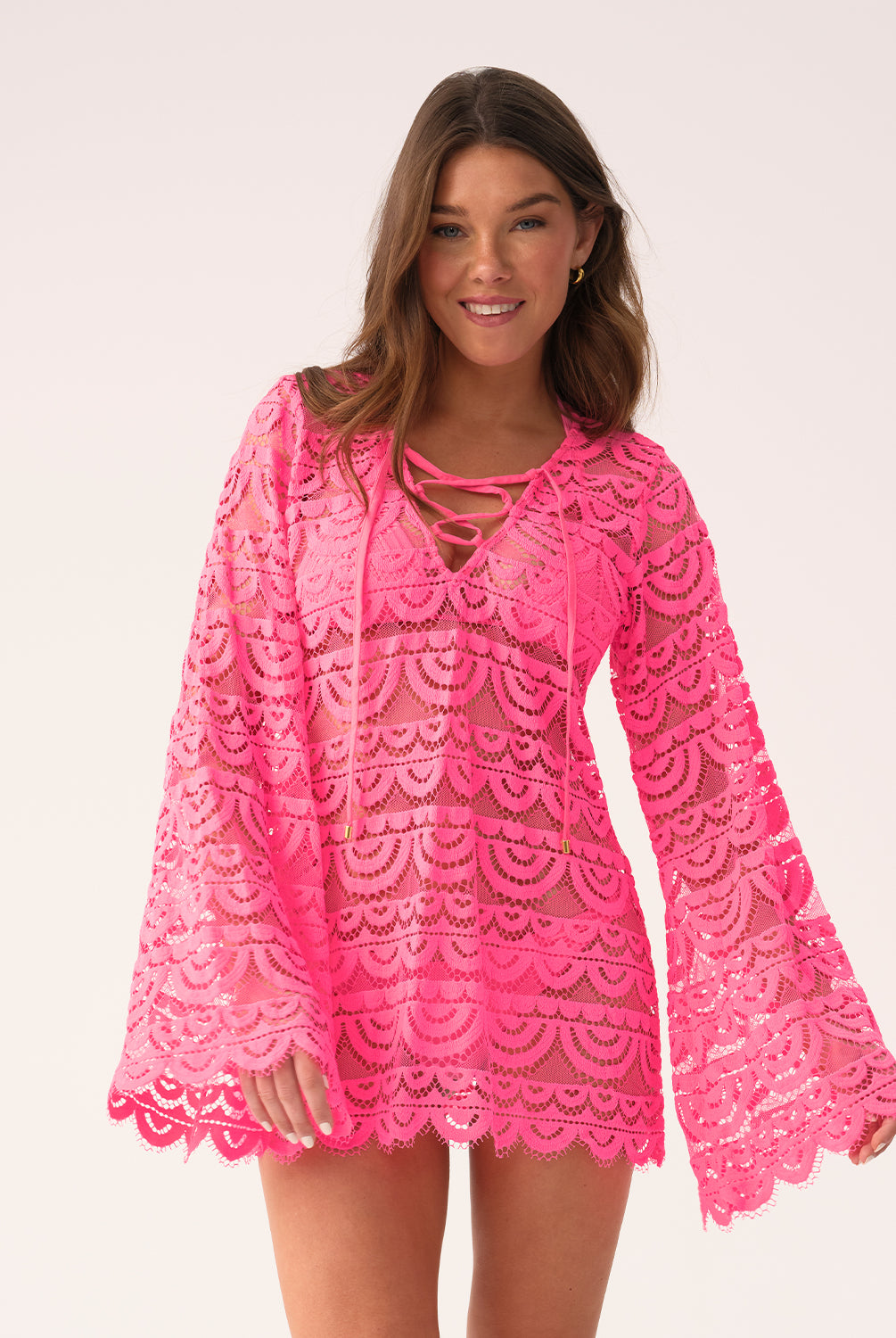 Woman wearing a bright pink lace dress on a white background