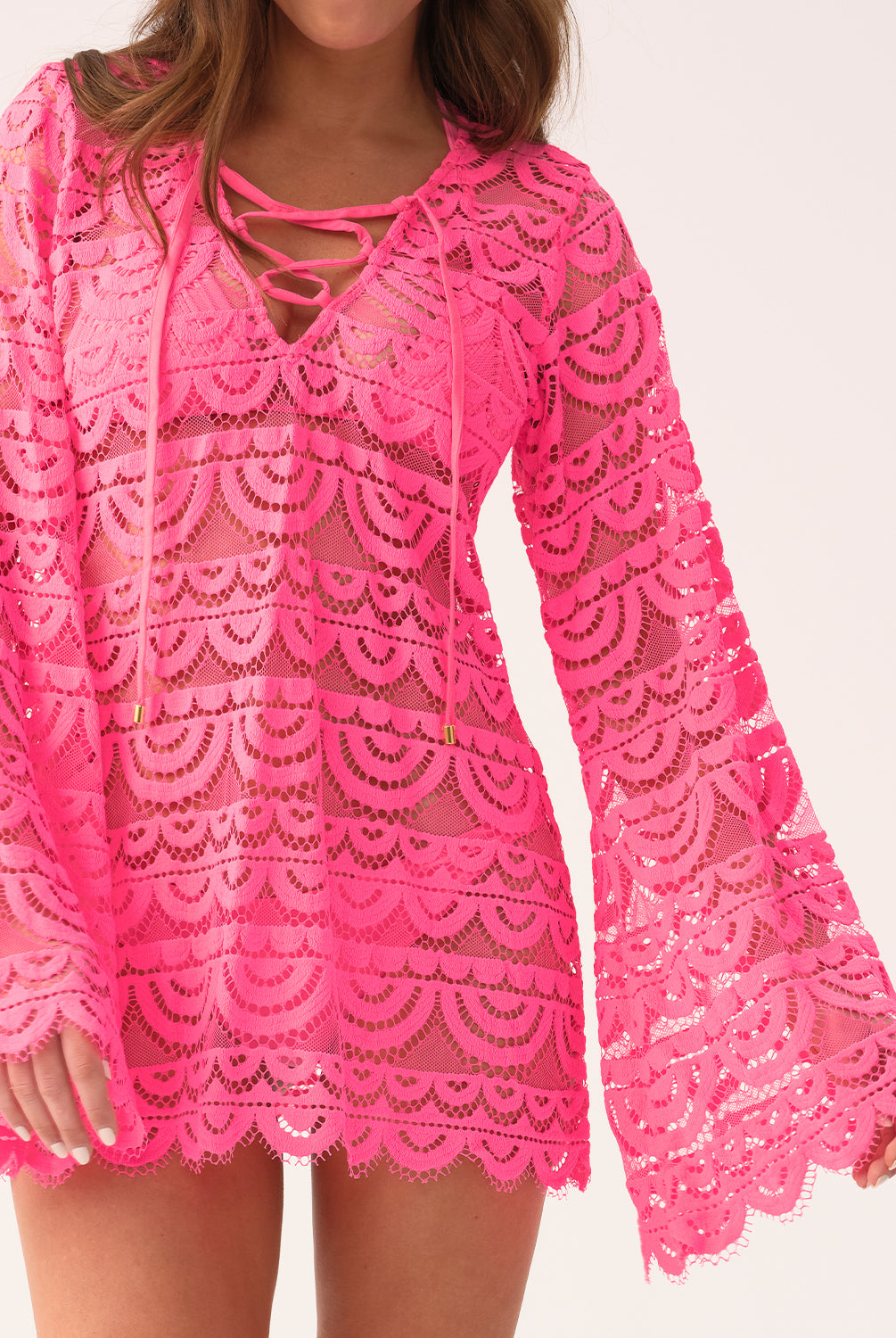 Woman wearing a pink lace cover-up dress on a white background