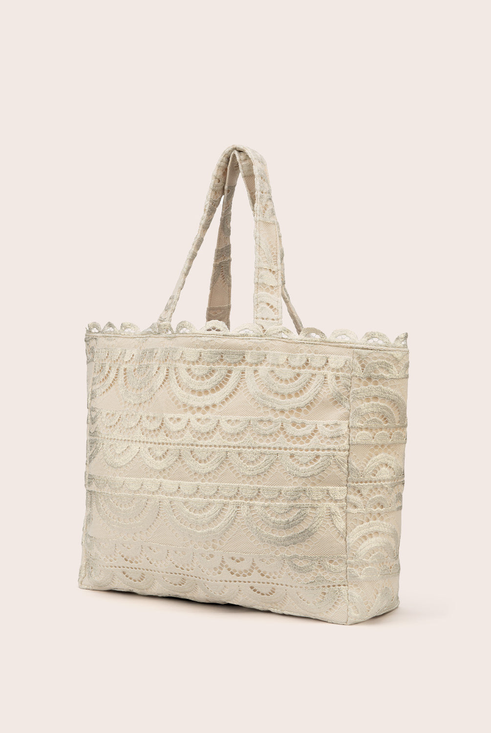 A tan lace tote with scalloped trim against a white wall.