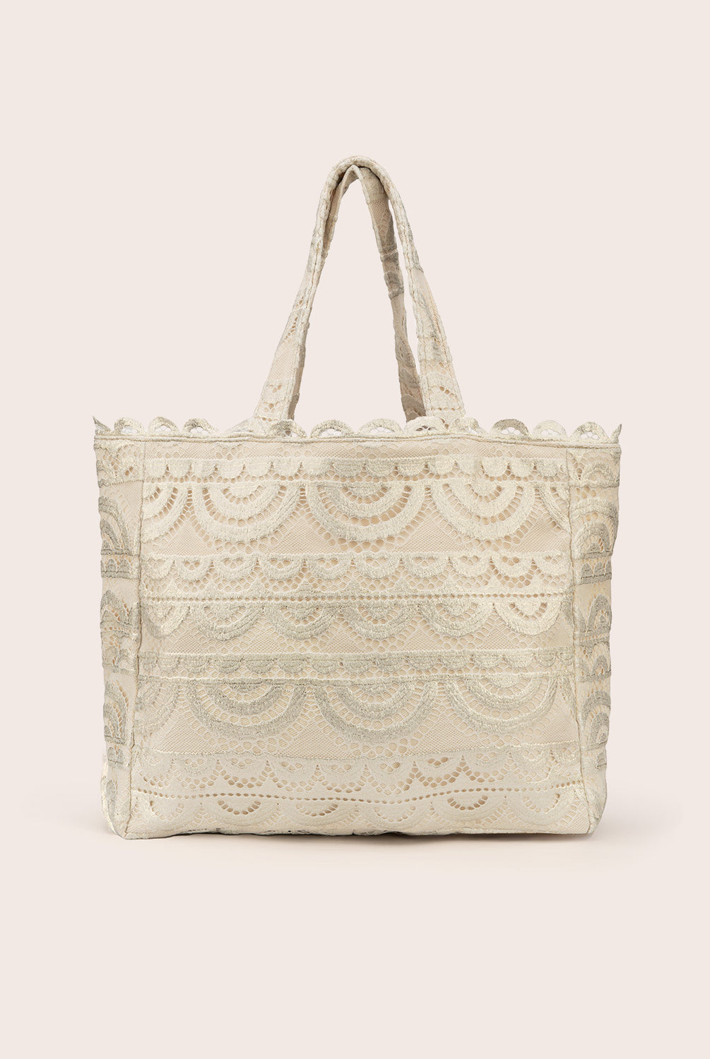 A tan lace tote with scalloped trim against a white wall.