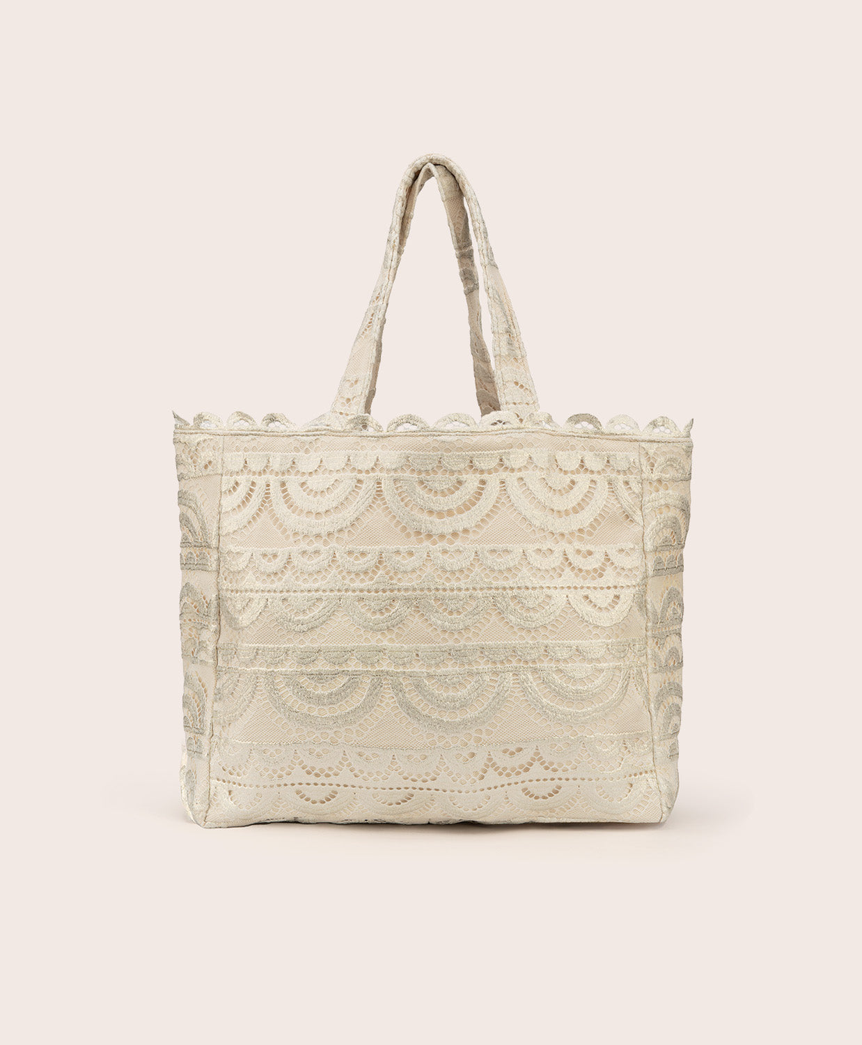 A tan lace tote with scalloped trim against a white wall.