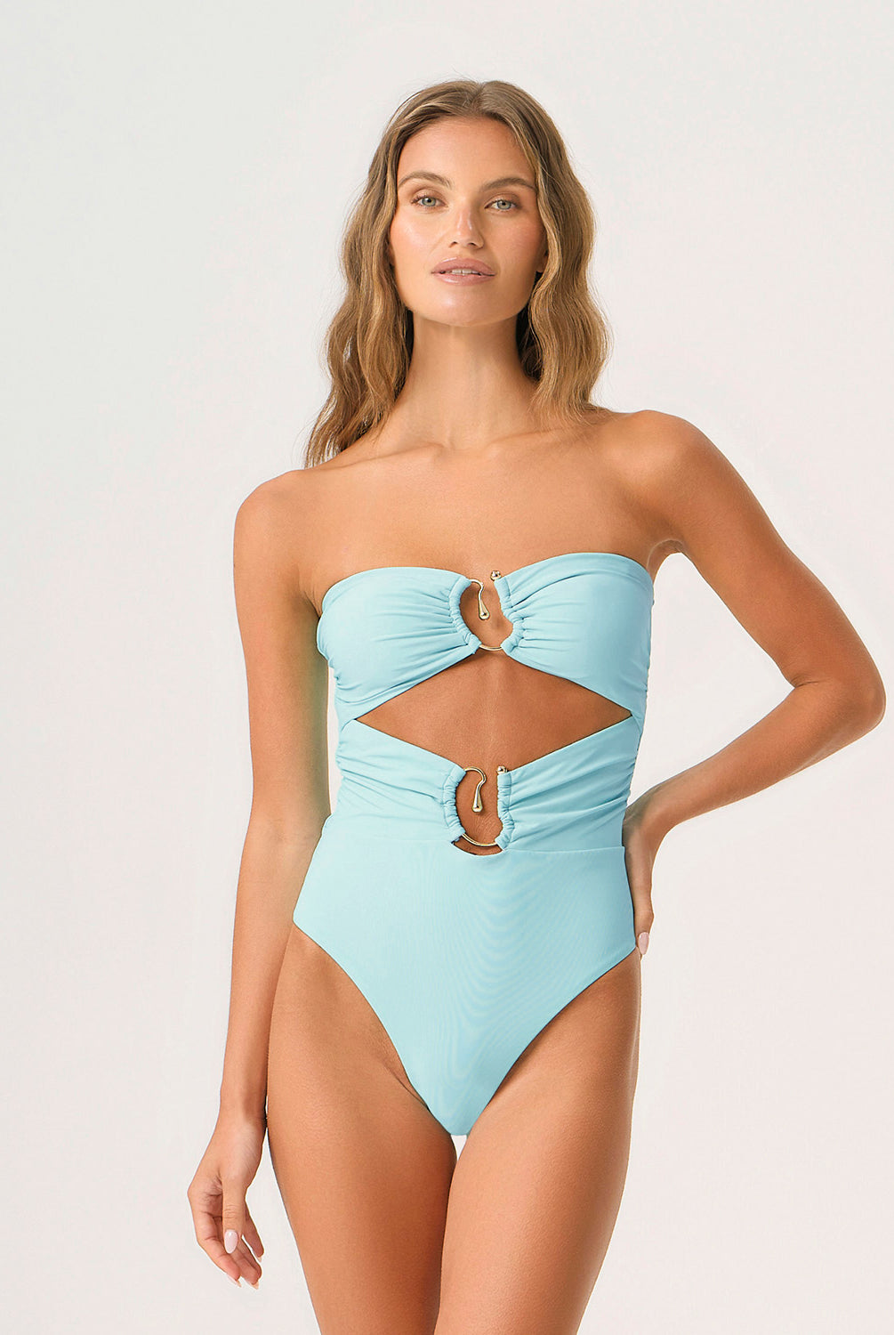 Woman wearing a light blue strapless swimsuit with cut-out design on a white background