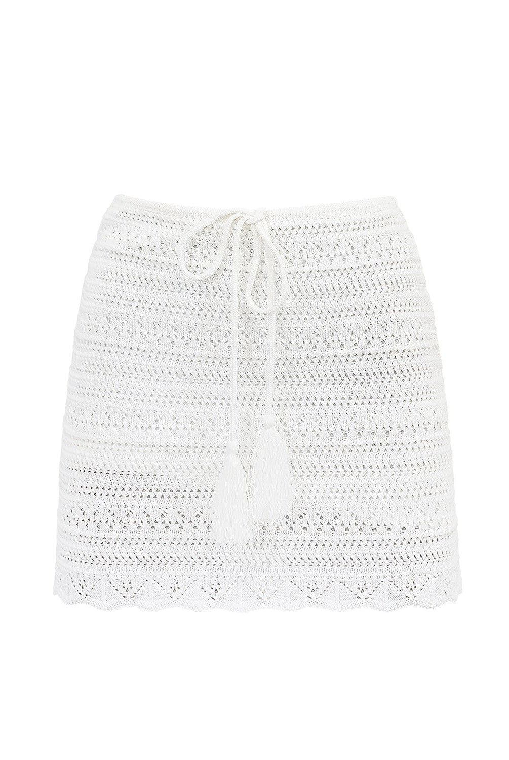 A white crochet skirt against a white wall. 