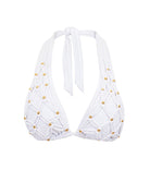A white bikini top with gold beads against a white wall.