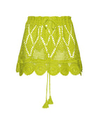 A green crochet skirt against a white wall.