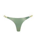 A green metallic bikini bottom against a white wall.