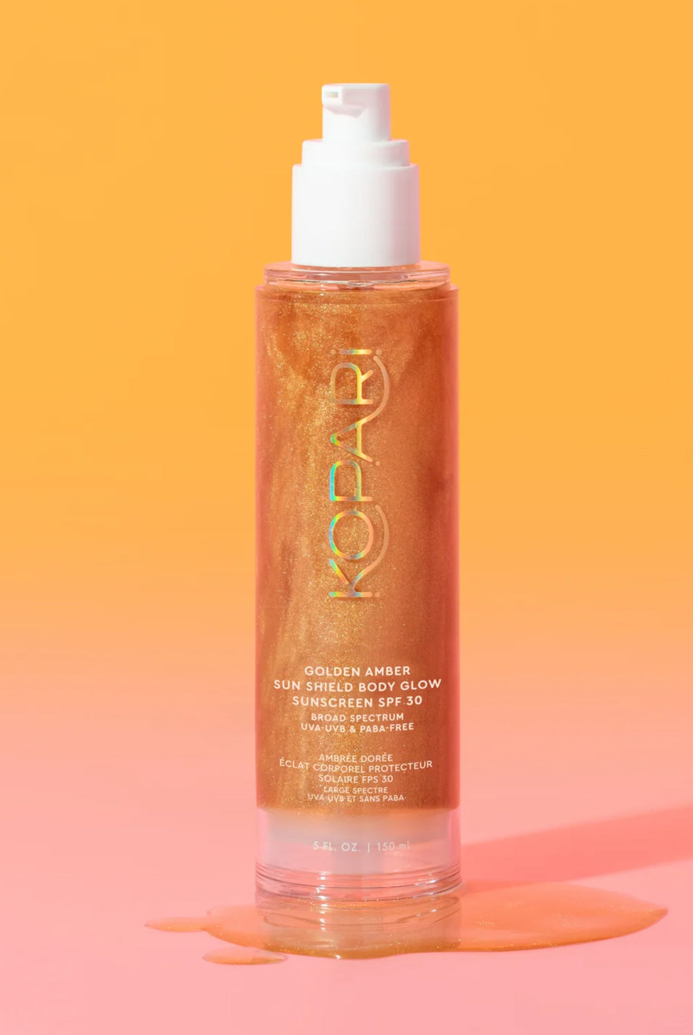 A tube of body glow sunscreen against an orange and pink wall.