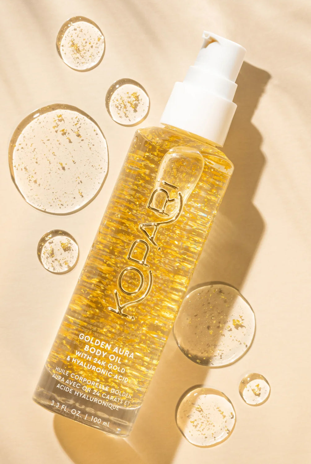 A tube of body oil with gold pieces against a yellow wall.