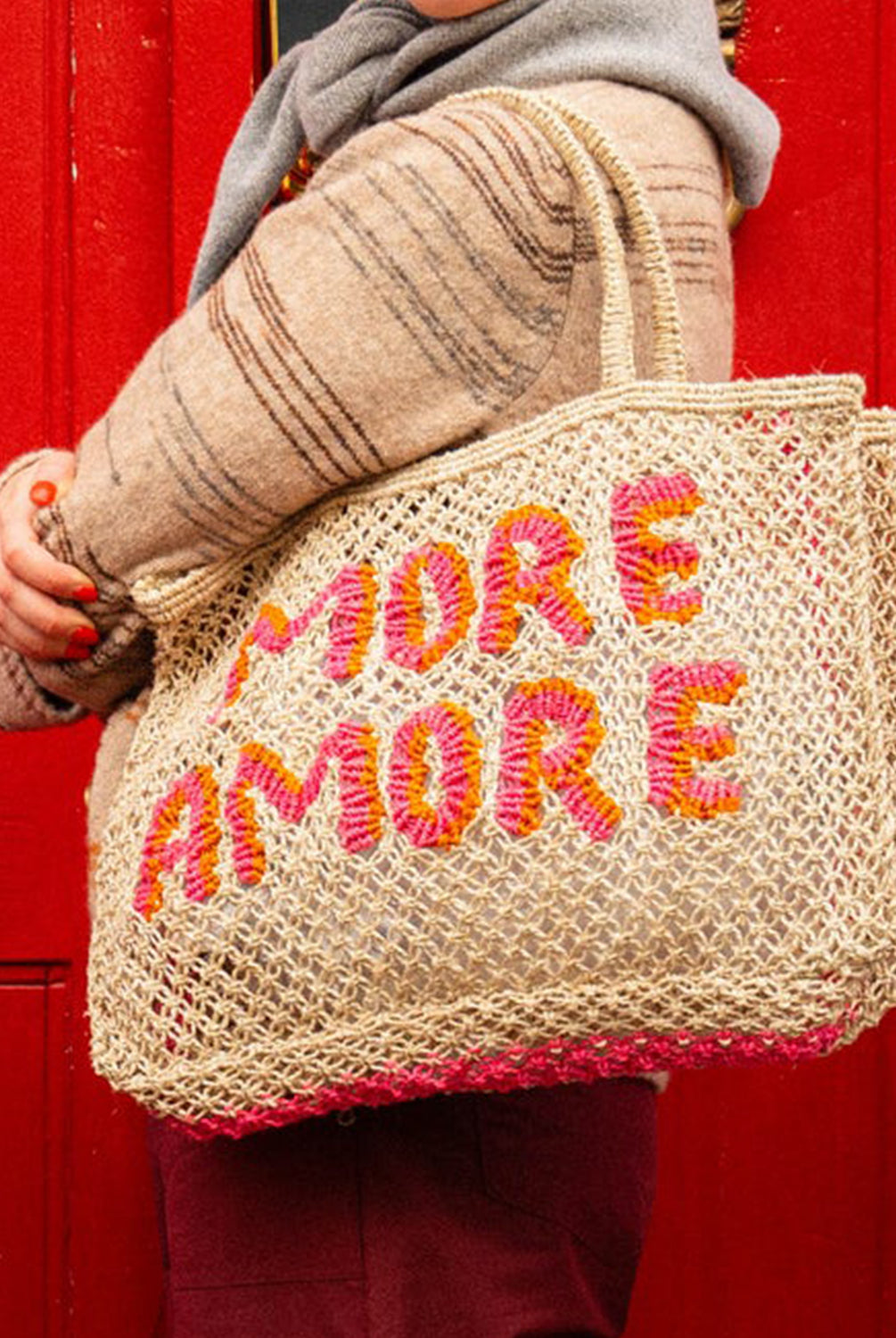 A woman holding a tote/bag that reads "More Amore" in pink and orange.